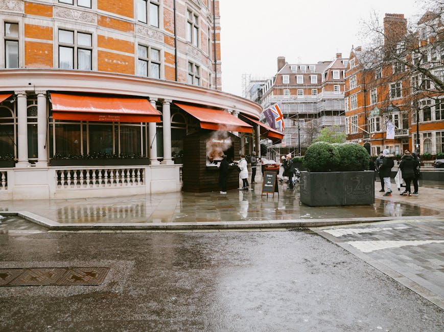 Public street view in Knightsbridge featuring a large Dior advertisement banner mounted on a historic building with ornate stonework and domed roof structures. In the foreground, a double-decker bus w
